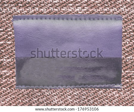 Blank bicolor leather jeans label on brown fabric background