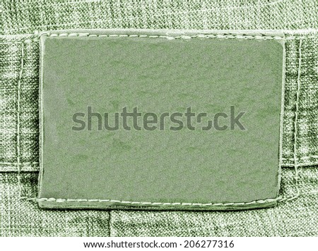 blank green  leather label on green jeans background