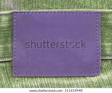 blank violet leather label on green jeans background