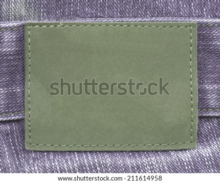 blank green jeans leather label on violet textile background