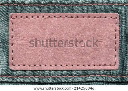red blank leather  label on green jeans background