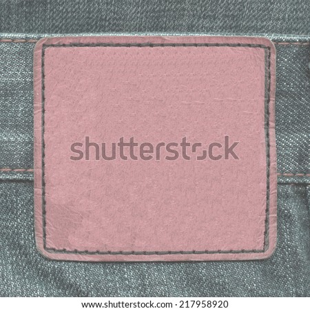 reddish  leather label on green jeans background