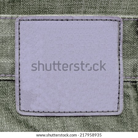 violet  leather square label on green jeans background
