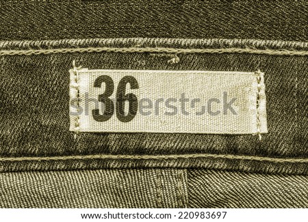 gray textile tag on gray-green jeans background, size