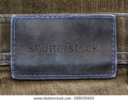gray-blue leather label on brown  jeans background