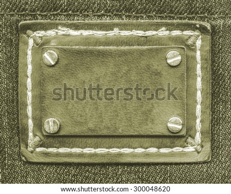 green leather label on green jeans background, buttons