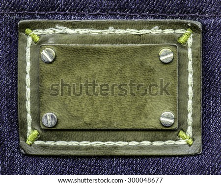 green leather label on violet jeans background, buttons