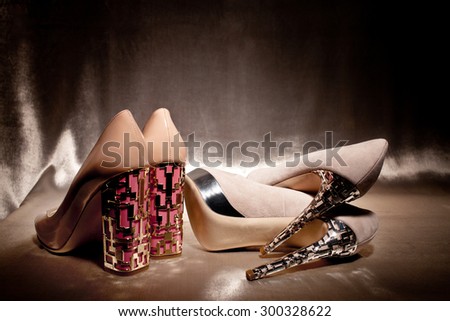 Two pairs glamour high heeled shoes on gold silk
