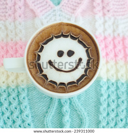 A cup of latte art on a knitted vest background
