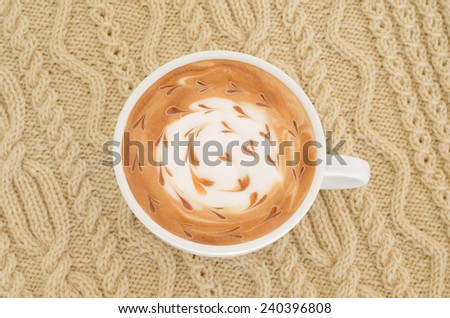 A cup of latte art on a knitted  background