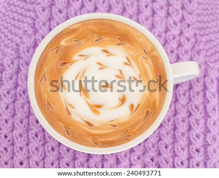 A cup of latte art on a knitted  background