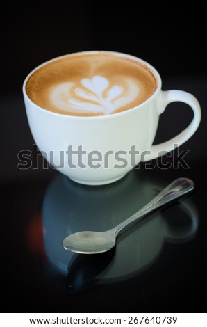 a cup of latte art on black background