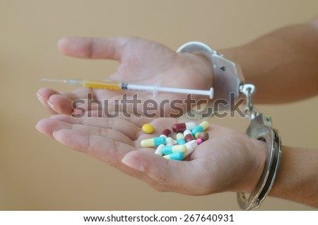 syringe and drug in hand and handcuffs