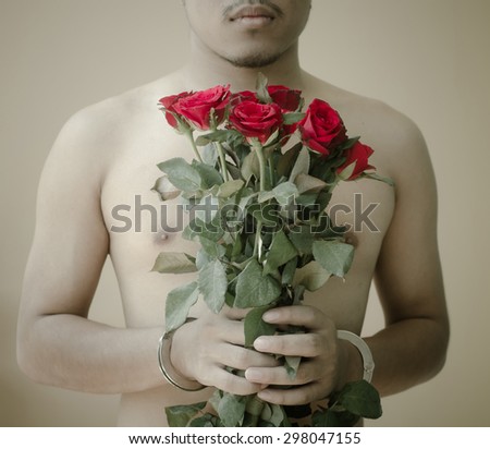 young man holding red rose in hand with handcuffs