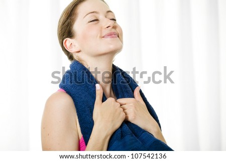 Happy young fitness woman holding towel around her neck