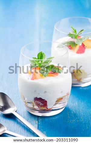 Close up photograph of a glass of yogurt with pieces of peach