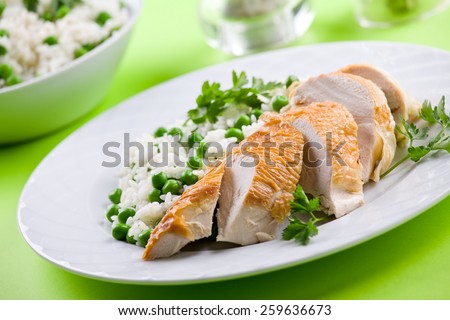 Chicken breast served with rice and peas