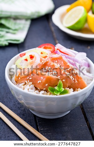 Close up of a bowl of sliced salmon with rice and vegetables