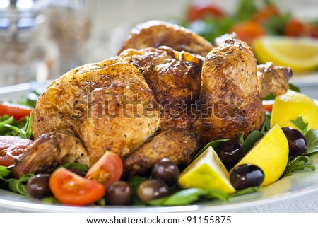 Close up photograph of a grilled chicken with tomato and olives
