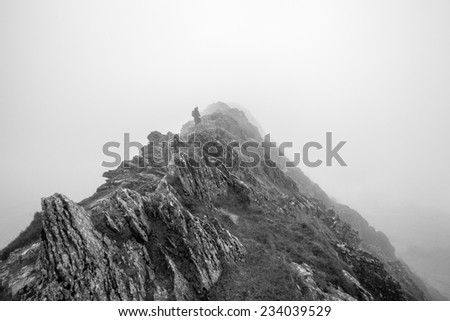 Man walking through fog on a mountain peak