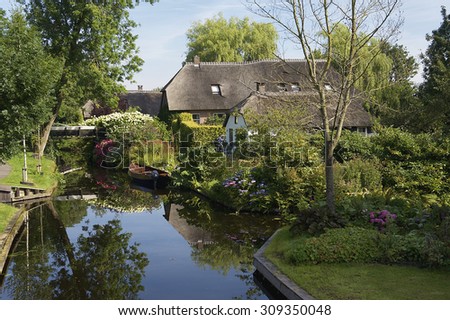 Lovely houses in the village Giethoorn with a boat in the canal. There is no car traffic; only boats.