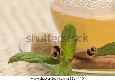 a close-up of a cup of tea with cane sugar cubes, cinnamon sticks and mint leaves