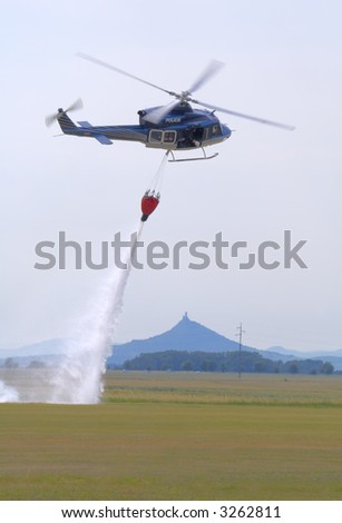 Bell-412 police helicopter dropping water to put out fire