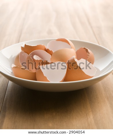 Cracked brown egg shells in a white bowl