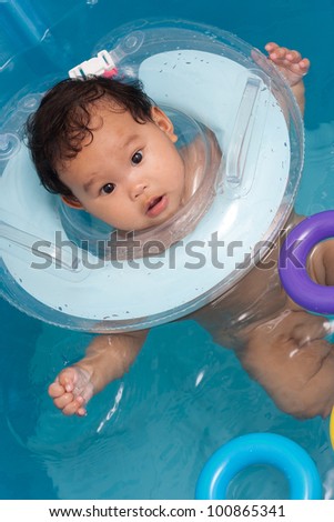 Baby swimming with neck swim ring in bath