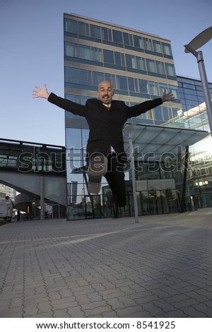 business man is jumping in front of his office complex