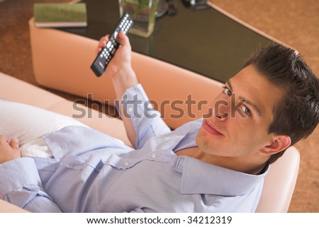 stock-photo-young-attractive-man-sitting-on-couch-watching-tv-34212319.jpg