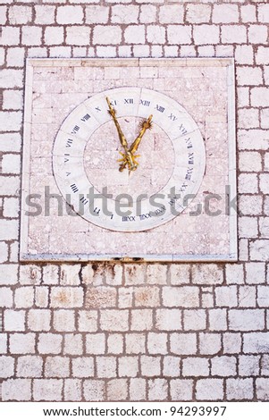 The stony clock on townhall in city Krk with golden hands and roman clock dial
