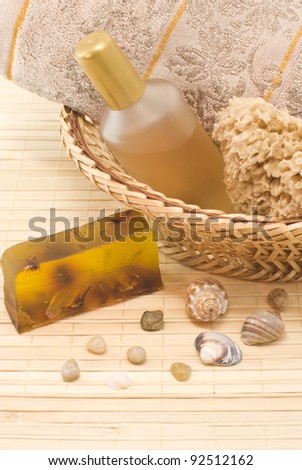 Natural soap, sponge, tonic and a soft towel in a wicker basket. Sea shells and semi-precious stones as a decorative element. Filmed in close-up on a bamboo napkin.