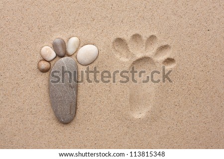 The footprint made up of stones on a sandy background