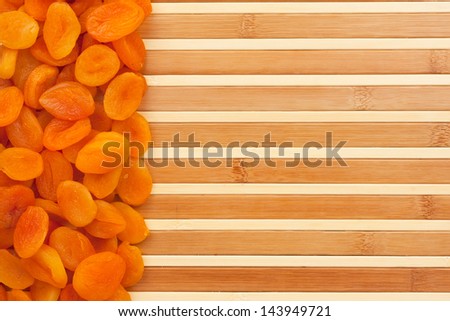 Dried apricots lying on a bamboo mat as background