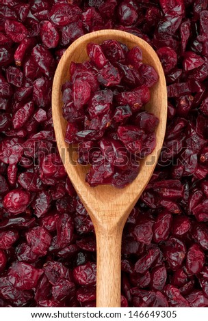 Wooden spoon with dried cranberries lies on the cranberries