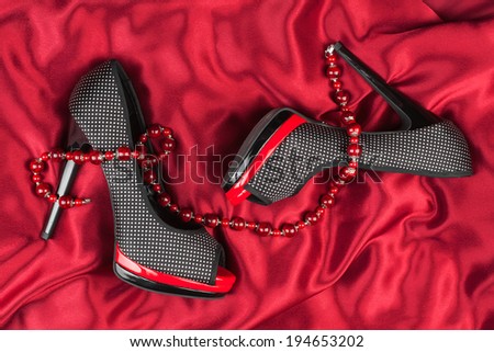 Red shoes, red beads lie on red fabric,can use as background