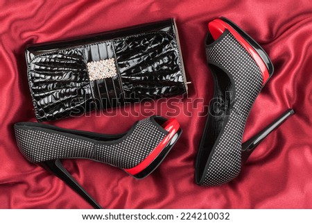 Shoes and bag  lying on red fabric, can be used as background