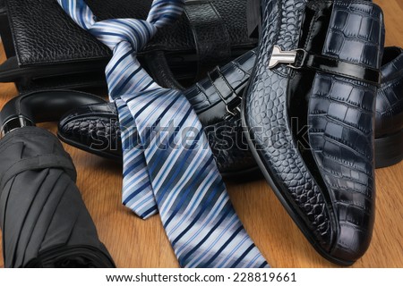 Classic men\'s shoes, tie, umbrella and bag on the wooden floor, can be used as background
