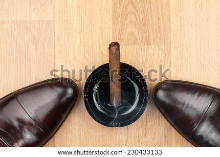 Classic men\'s shoes, ashtray and  fuming cigar on the wooden floor