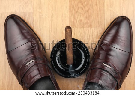 Classic men\'s shoes, ashtray and  fuming cigar on the wooden floor