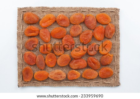 Frame made of burlap with dried apricots, on a white background