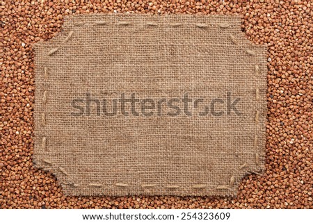 Figured frame with burlap and stitches with  place for your text lying on buckwheat  grains as a background