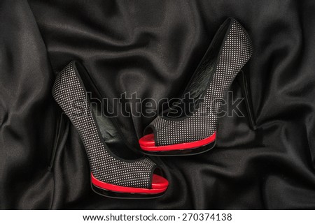 High-heeled shoes lying on black  fabric, can use as background