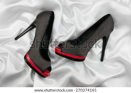 High-heeled shoes lying on white  fabric, can use as background