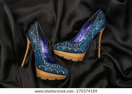 High-heeled shoes  lying on black  fabric, can use as background