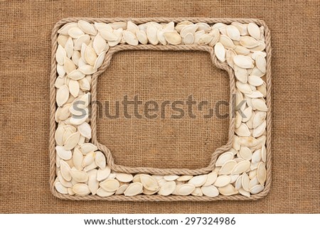 Two frames made of rope with pumpkin seeds on sackcloth, as background, texture
