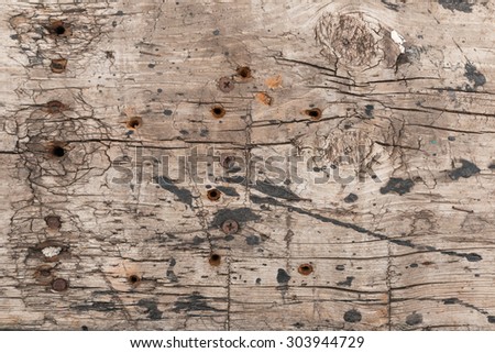 Old wooden surface with holes, screws, nails and soiled black paint