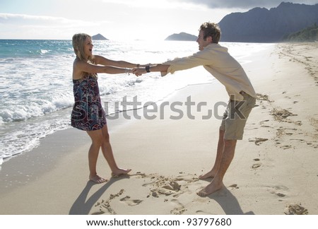 A beautiful young couple play around on the beach in Hawaii