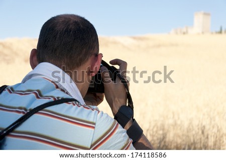 Photographer taking a picture of the Penaranda de Duero Castle (out of focus). It is a fortress which is located on a hill in the town of Penaranda de Duero (Burgos, Spain)